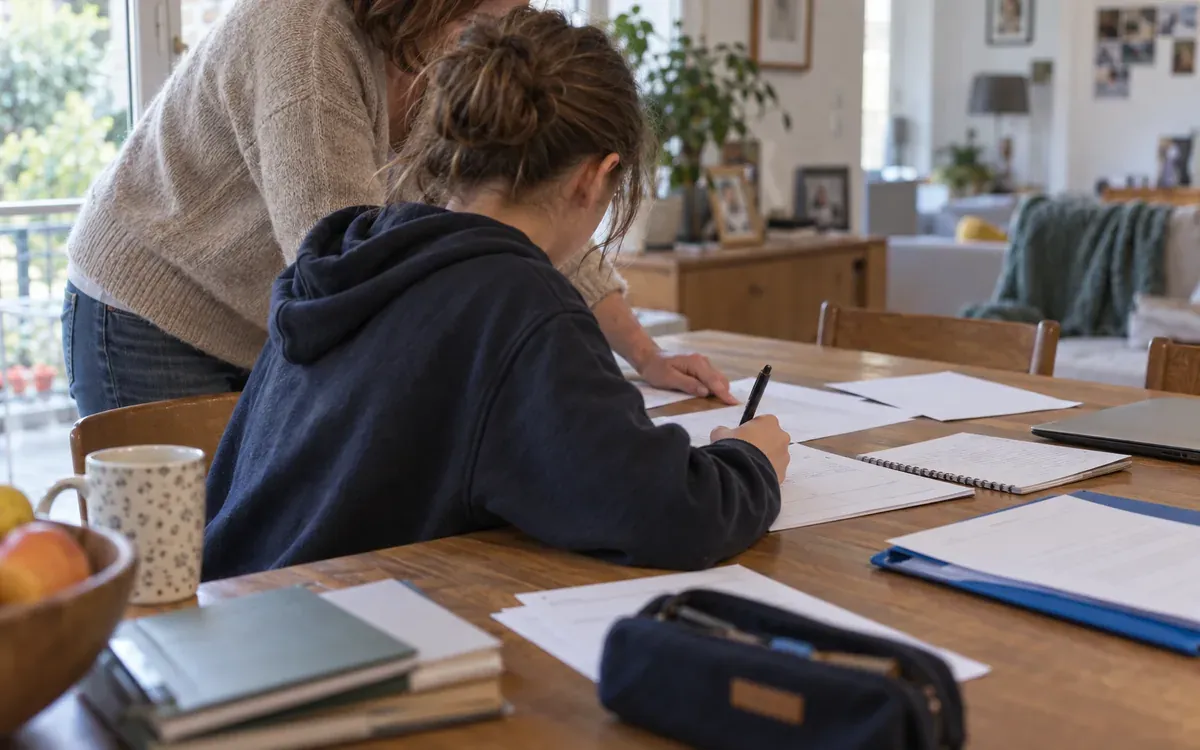 Collégien préparant un dossier de stage à table avec un parent